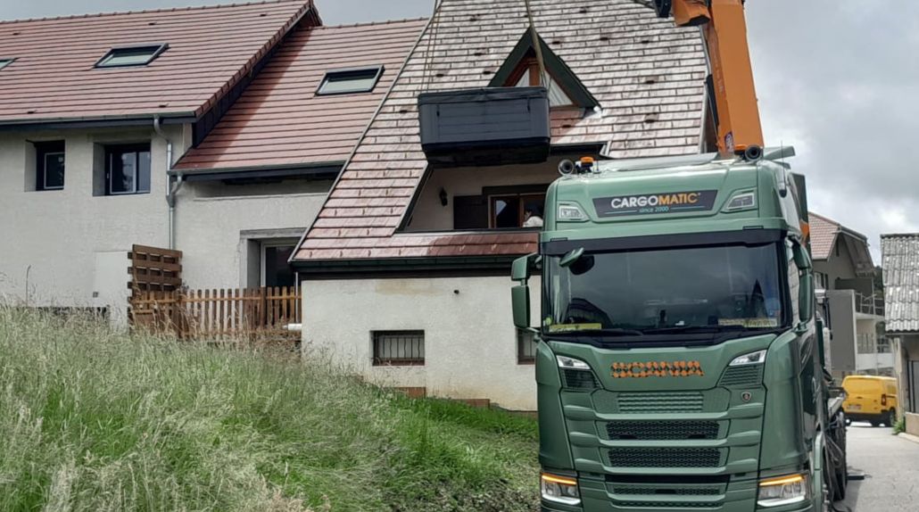 Une grue qui dépose un spa dans le toit d'une maison
