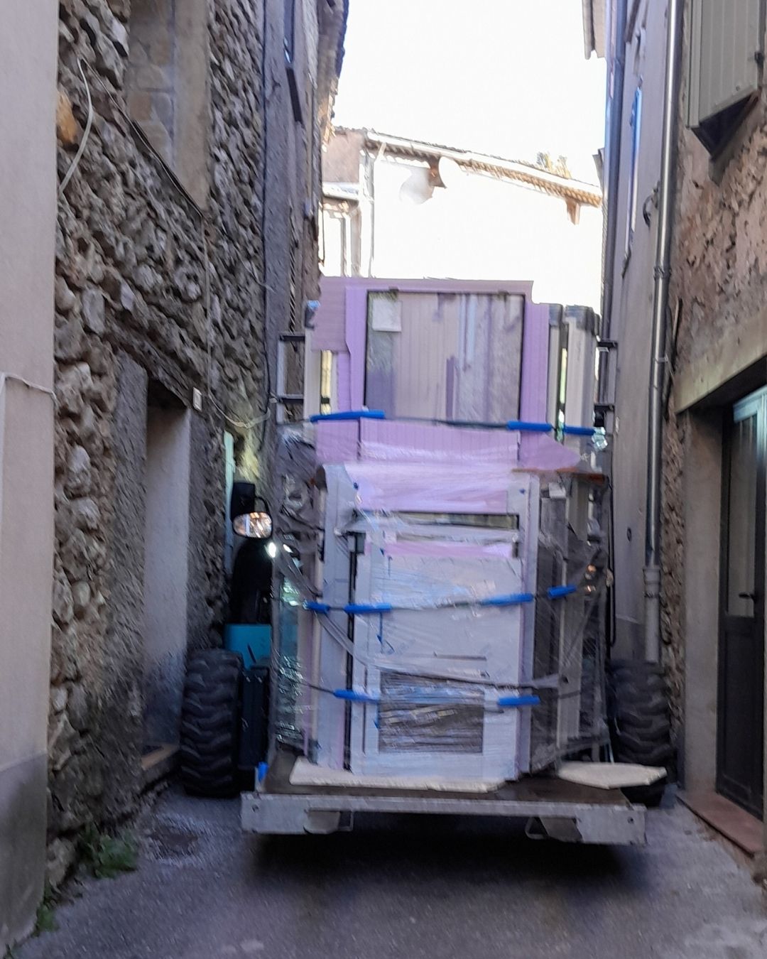 Chariot embarqué manœuvrant une véranda en accès difficile dans une rue étroite, opération logistique Cargomatic
